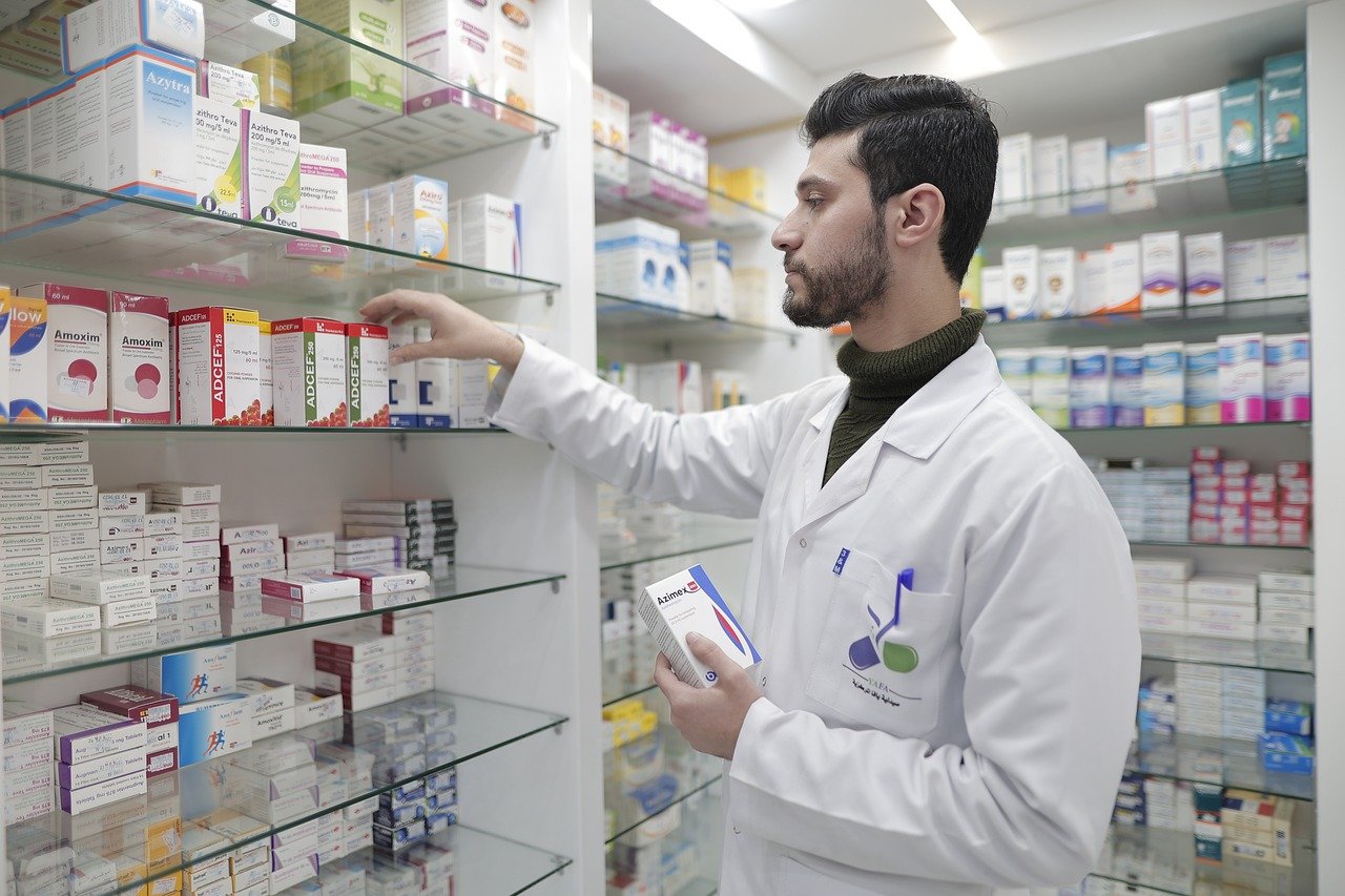 Pharmacist stocking shelves with hay fever remedy